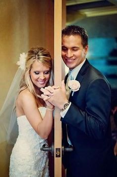 a bride and groom standing in front of a door with their hands on each other