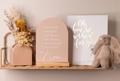 a wooden shelf with two greeting cards and a stuffed animal on it next to a card holder