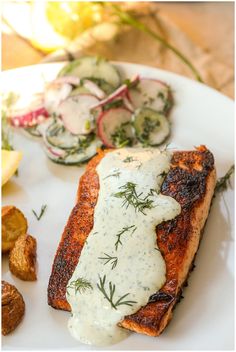 grilled salmon with dill sauce and cucumbers on a white platter