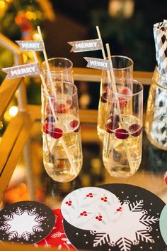 three glasses filled with liquid sitting on top of a table next to paper snowflakes