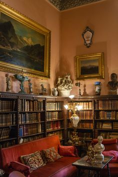 a living room filled with lots of furniture and bookshelves covered in paintings on the walls