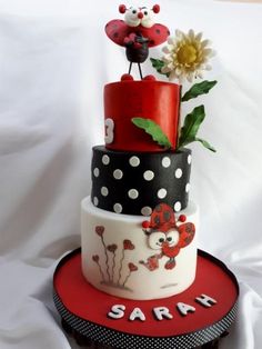 a three tiered cake decorated with ladybugs, flowers and polka dot designs