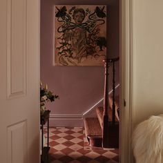 a hallway with a painting on the wall and stairs leading to another room that has a checkerboard floor