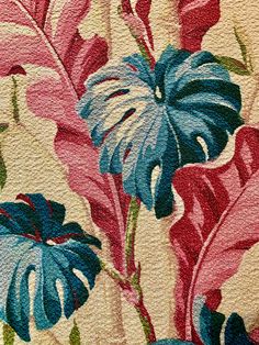 a close up view of a flower on a wallpapered surface with blue, pink and green leaves