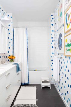 a bathroom with blue and white polka dots on the walls, shower curtain, rugs, and bathtub