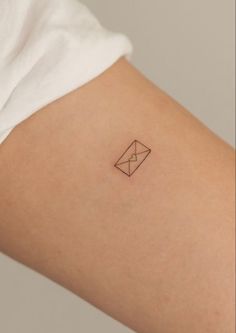 a small tattoo on the back of a woman's left arm that has an envelope in it