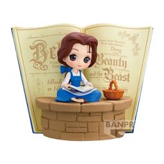 a figurine sitting on top of a brick wall next to an open book