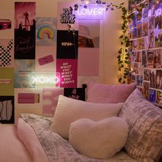 a bed with lots of pillows on top of it next to a wall covered in pictures