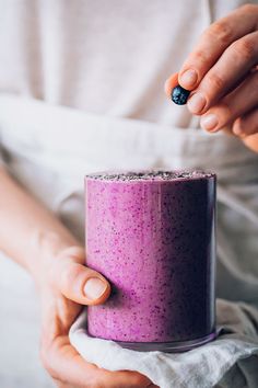 a woman is holding a purple cup with black speckles on it and she has her hands in the cup