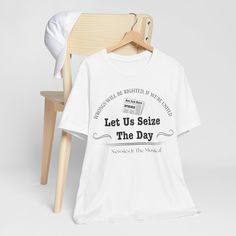 a white t - shirt that says let us seize the day next to a wooden chair