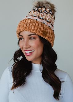 Look cute and stay warm all winter long in this super soft chenille feel hat! Our new collection of pom hats is one you won't want to miss out on! This knit winter hat features fleece lining and a faux fur pom accent.  Camel and multicolored patterned knit pom hat Natural faux fur pom accent Fleece lined Crown patch on the left side One size Designed in the U.S.A. Produced in China. 100% Polyester Pom Hats, Knit Winter Hat, Knitted Hats Kids, Knit Jewelry, Dangle Necklaces, Animal Books, Winter Hats For Women, Faux Fur Pom Pom, Pom Pom Hat