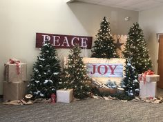 decorated christmas trees and presents in front of a sign that reads peace joy on it