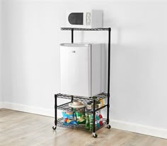 a white refrigerator sitting on top of a metal shelf next to a wall and wooden floor