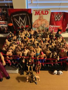 a large group of toy wrestlers are posed in front of a wrestling ring