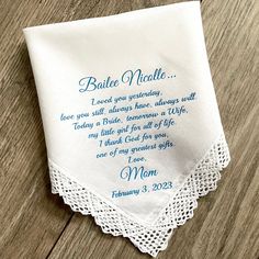 a white handkerchief with a poem on it sitting on top of a wooden table next to a pen