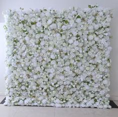 white flowers are arranged on the side of a wall