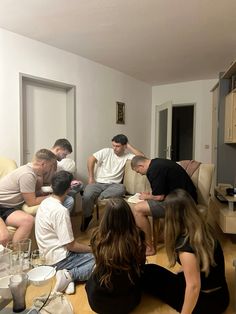 a group of people sitting on top of a couch in a living room next to each other