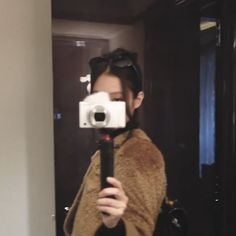 a woman taking a selfie in front of a mirror with a camera attached to her shoulder