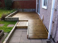 a wooden deck with steps leading up to the back door and patio area next to it