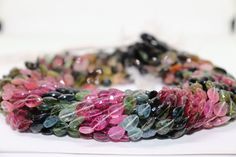 a close up of a bracelet made out of glass beads and other colored stones on a white surface