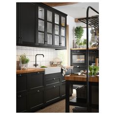 a kitchen with black cabinets and wooden counter tops is pictured in this image, there are potted plants on the shelf