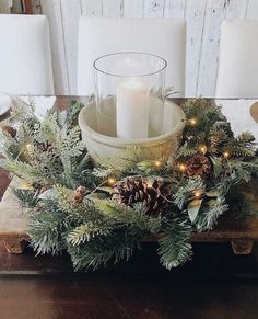 a wooden table topped with a candle and pine cones