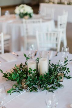 candles and greenery are arranged on the table