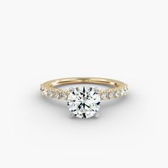 a yellow gold engagement ring with a round brilliant diamond set in the center and side stones