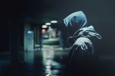 a person in a hooded jacket walking down a dark hallway