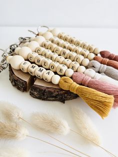 several beads with tassels are arranged on a piece of wood and some feathers