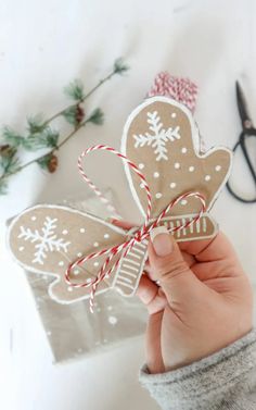 a person holding up a paper cut out of a gingerbread heart with snowflakes on it