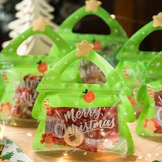 three green christmas bags sitting on top of a table covered in candy and candies