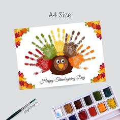 a thanksgiving card with a turkey handprinted on it and watercolors next to it