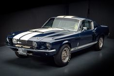 an old blue mustang with white stripes on it's hood in a dark room