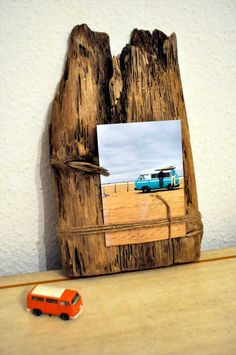 an orange toy car is parked in front of a wooden photo frame