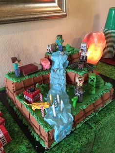 a cake made to look like a waterfall with legos on top and other items around it