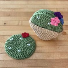 two small crocheted cactus hats sitting on top of a wooden table next to each other