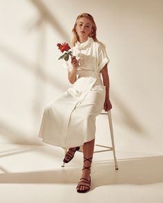 a woman sitting on a chair with a flower in her hand and holding a red rose