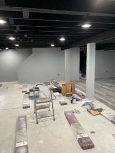 an empty room with several pieces of furniture scattered on the floor, including ladders and boxes