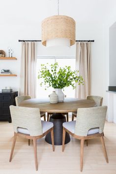 a dining room table with four chairs and a potted plant on top of it