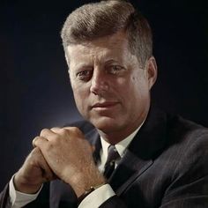 a man in a suit and tie is posing for a photo with his hand on his chin