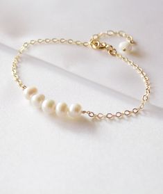 "Gold White Freshwater Pearl Bracelet. The most dainty & delicate bracelet, perfect for wedding jewerly or everyday wear. //ITEM DETAILS// - White Freshwater Pearls measures approx 5mm-5.5mm Pearls are wire wrapped in gold fill wire, and finished off with a gold filled spring clasp and 1-inch extender chain - 14k gold filled, Rose Gold Fill, Sterling Silver spring clasp and findings //ORDER INSTRUCTION// - Please choose materials and size from drop down menus. - The note/quote you want in th Wedding Pearl Bracelet, Bridesmaid Pearl Earrings, Pearl Bracelet Wedding, Bridesmaid Pearls, Bracelet Wedding, Wedding Gifts For Bride, Wedding Party Gift, Bracelet Dainty, Freshwater Pearl Bracelet