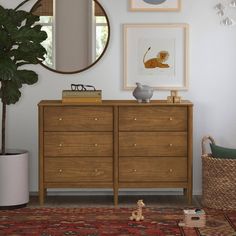 a room with a dresser, mirror and potted plant on the floor next to it