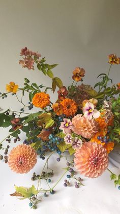 an arrangement of flowers on a white surface