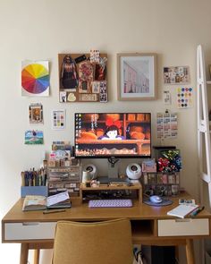 a desk with a computer monitor, keyboard and many pictures on the wall