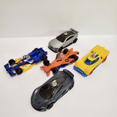 several toy cars are lined up on a white surface with one car in the middle