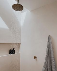 a shower head with rain coming out of it next to a bathtub and towel rack