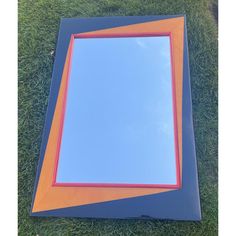 a mirror sitting on top of a green grass covered field next to a blue sky