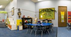 a classroom with tables, chairs and bookshelves filled with children's toys