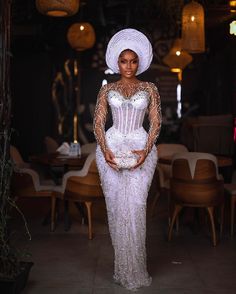 a woman in a white dress and headdress posing for the camera with her hands on her hips